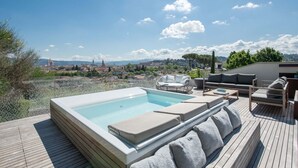 Une terrasse sur le toit avec un jacuzzi, des sièges extérieurs et une vue sur une ville historique.
