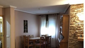 Een eetgedeelte met een houten tafel en stoelen, een accentmuur van steen en een betegelde vloer.
