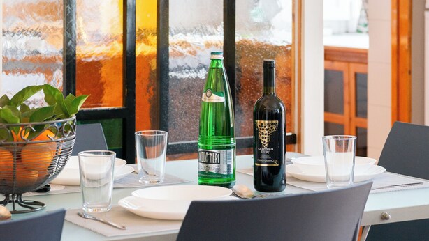 Une table à manger avec une bouteille de vin, une bouteille verte et des verres.