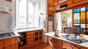Une cuisine avec des meubles de rangement en bois, une fenêtre et un coin repas comprenant une table et des chaises.