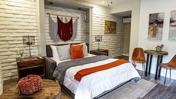 A modern bedroom with a large bed, a wooden coffee table, a small round table, and a decorative pumpkin.