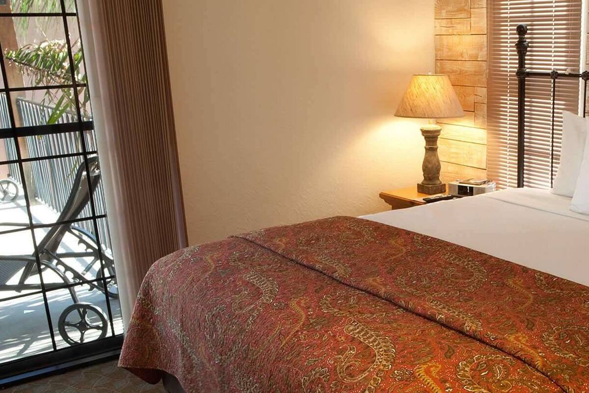 A neatly made bed with a patterned bedspread, a bedside lamp, and a metal headboard.