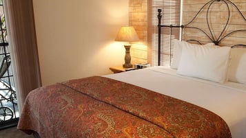 A neatly made bed with a patterned bedspread, a bedside lamp, and a metal headboard.