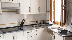 Une cuisine avec des armoires blanches, un évier à deux bacs et un four encastré.