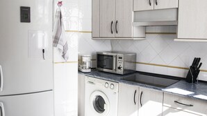 Une cuisine compacte équipée d’un lave-linge, d’un four à micro-ondes et d’une machine à café.
