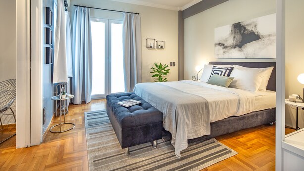 A modern bedroom with a large bed, a bench, a small table, and a potted plant. - UPSTREET Superb 1BD Apt-Heart of Kolonaki (Athens)