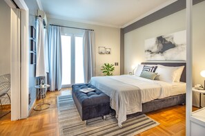 A modern bedroom with a large bed, a bench, a small table, and a potted plant. - UPSTREET Superb 1BD Apt-Heart of Kolonaki (Athens)
