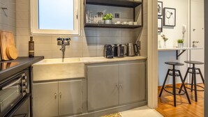 A modern kitchen with grey cabinets, a built-in oven, and a window above the sink. - UPSTREET Superb 1BD Apt-Heart of Kolonaki (Athens)