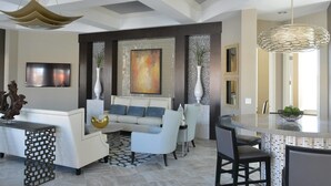 A modern living room with a white sofa, a coffee table, and a dining area with a glass table and chairs. - Stylish and Stunning 5BD Pool Home in Solterra - #5st452 (Davenport)