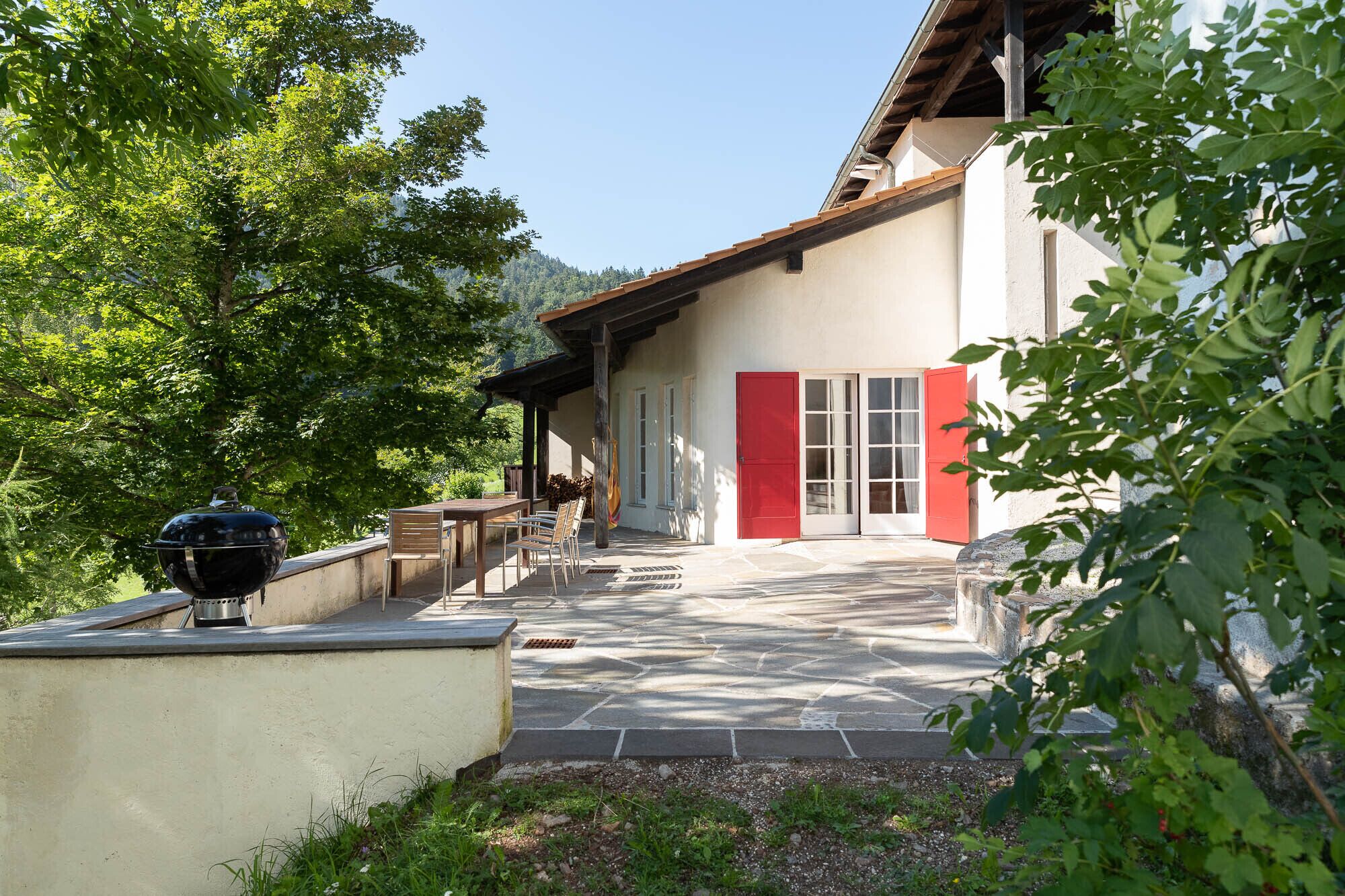 Une maison avec un patio, un barbecue et une porte rouge.