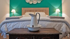A bedroom with a bed, two bedside lamps, a wooden nightstand with a white vase, and a teal wall with decorative elements. - RURAL HOUSE IN SIERRA DE ARALAR, 4O KM FROM SAN SEBASTIAN-30 PAMPLONA 12 PEOPLE (Baráibar)