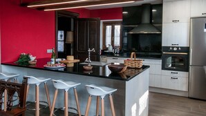 A modern kitchen with a central island, bar stools, stainless steel appliances, and a red accent wall. - RURAL HOUSE IN SIERRA DE ARALAR, 4O KM FROM SAN SEBASTIAN-30 PAMPLONA 12 PEOPLE (Baráibar)