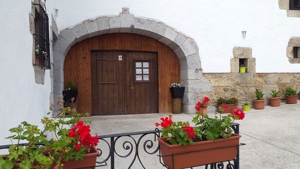 A rustic building with a wooden door, stone archway, and potted plants in front. - RURAL HOUSE IN SIERRA DE ARALAR, 4O KM FROM SAN SEBASTIAN-30 PAMPLONA 12 PEOPLE (Baráibar)