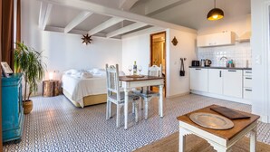 A room with a bed, a dining table with chairs, a small kitchen area, and a blue cabinet. - Studio gound floor with garden and Sea Views (Tarifa)