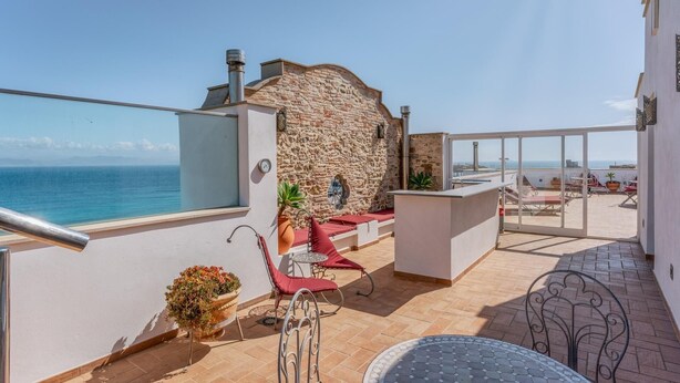 Een balkon met een stenen muur, uitzicht op zee en buitenmeubels.