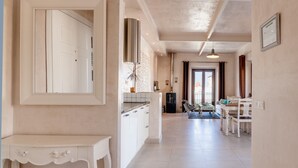 Een ruime keuken met een centraal eiland, een eethoek met tafel en stoelen, en uitzicht op de stad door het raam.