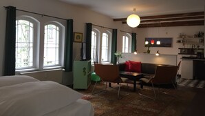 Une pièce comprenant un lit, un bureau avec des chaises, une table à manger et un coin cuisine.