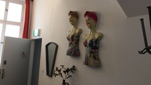 Une pièce comprenant deux sculptures fixées au mur, une porte portant un numéro, un miroir et une plante.