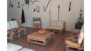 A rustic room with a wooden coffee table, a striped chair, and a bed with a striped blanket. - CALLAU HOUSE Poble Nou (Poblenou del Delta)