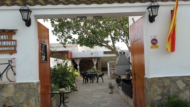 An outdoor patio area with stone flooring, tables, chairs, and a grill. - CALLAU HOUSE Poble Nou (Poblenou del Delta)