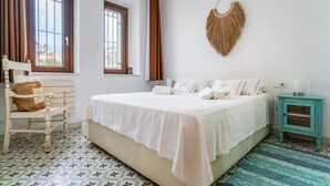 A bedroom with a bed, a chair, a small table, and a wall-mounted decorative item. - Apartment porch and garden (Tarifa)