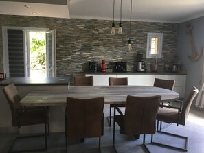 Cozinha moderna com painel de backsplash em pedra, ilha central com assentos e diversos eletrodomésticos.