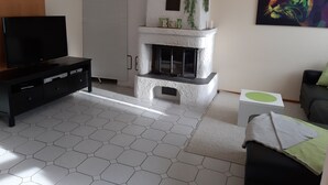 A modern living room with a fireplace, a flat-screen TV, and a painting. - Idyllic and quietly located vacation apartment in the university town of Idstein🌳 (Idstein)