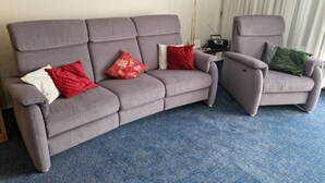 A grey sofa with red and white cushions, a grey armchair with a green cushion, and a floor lamp. - Unwind, relax, recover ... - Indoor swimming pool (12x6m) u. Sauna in the house! (Unterkirnach)