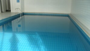 A swimming pool with a tiled floor and a metal ladder. - Unwind, relax, recover ... - Indoor swimming pool (12x6m) u. Sauna in the house! (Unterkirnach)