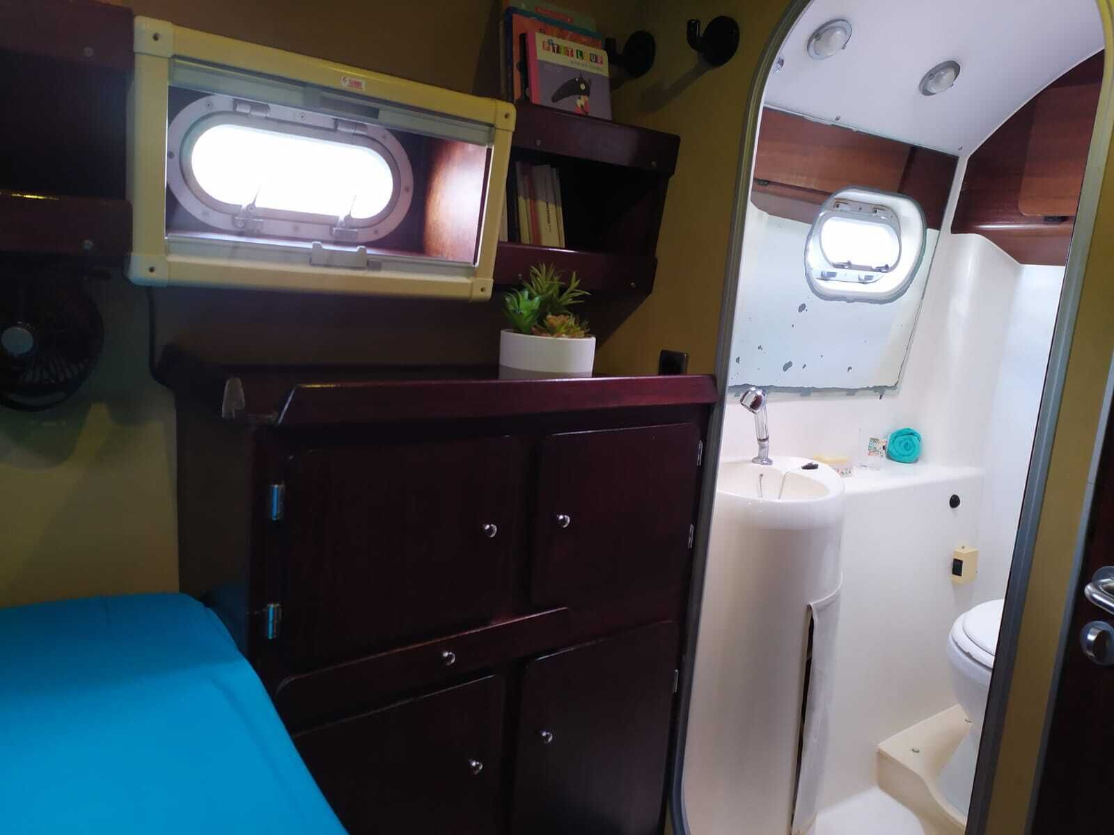 Ein kleines Badezimmer mit Fenster, Waschbecken und Toilette.