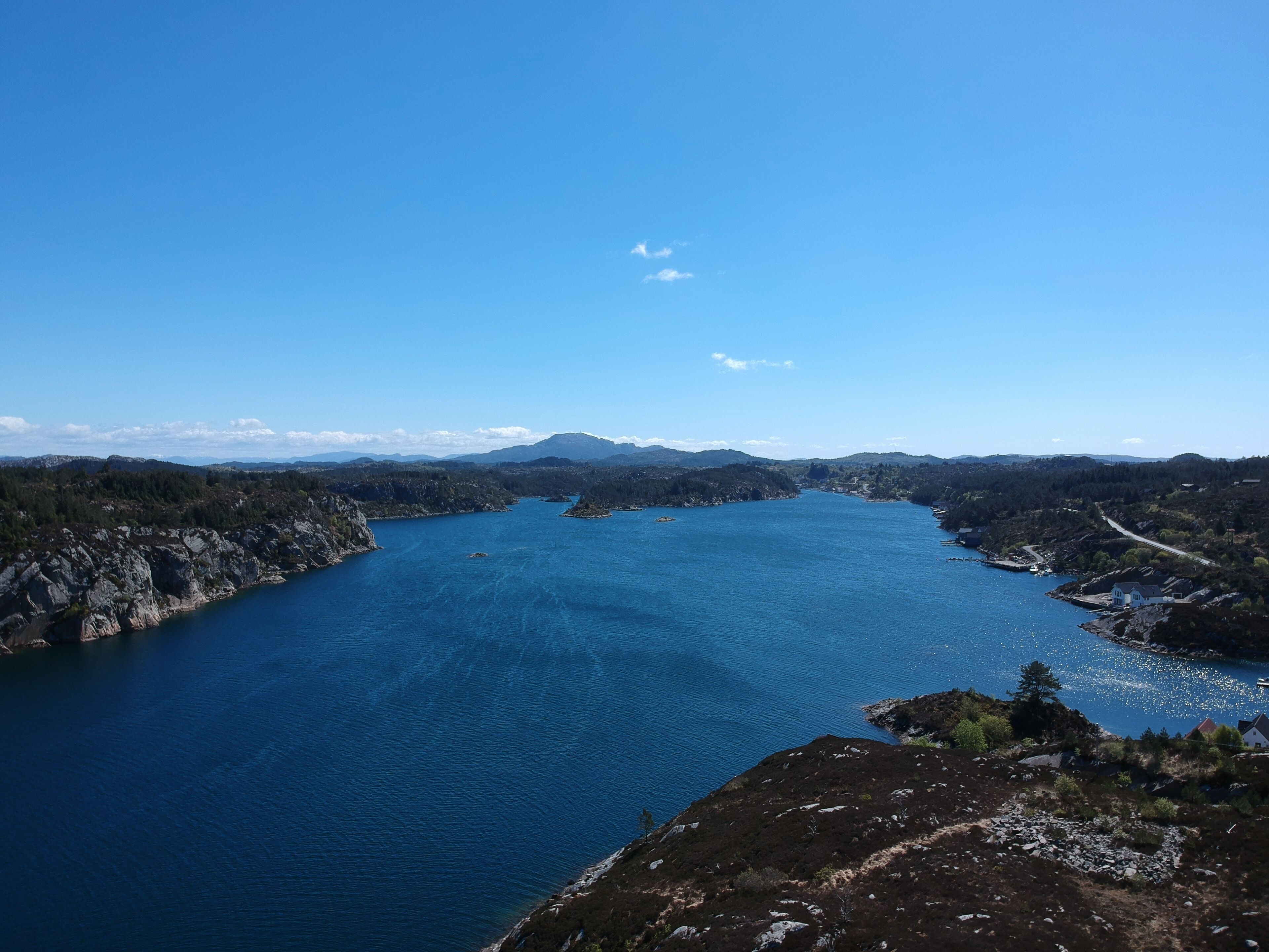 A coastal landscape with a large body of water, rocky shores, and a clear sky.