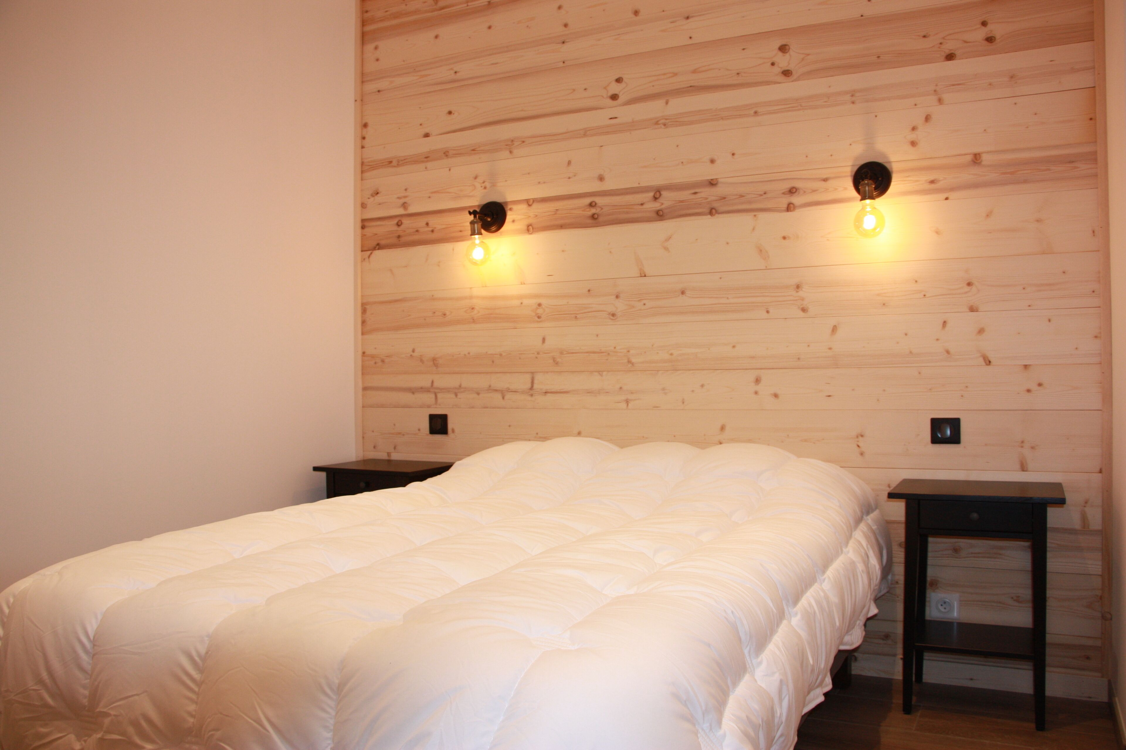 A bedroom with a wooden headboard, a large bed, and two bedside tables.