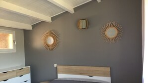 A bedroom with a bed, a dresser, two round mirrors, and a window.