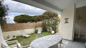 A patio with a table and chairs, a covered area, and a view of trees and a fence.