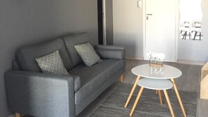 A modern living room with a grey sofa, a round coffee table, and a hanging light fixture.