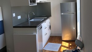 Eine kleine Küche mit Mikrowelle, Backofen und Kühlschrank.