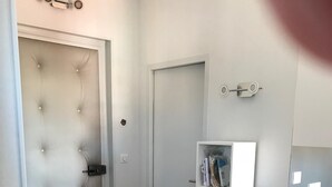 Ein gemütlicher Raum mit einer gepolsterten Tür, einem kleinen runden Tisch, einem bunten Stuhl, einem Bücherregal und einem weißen Schrank.