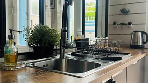 Une cuisine moderne dotée d’un plan de travail en bois, d’un évier en acier inoxydable et d’un égouttoir à vaisselle.