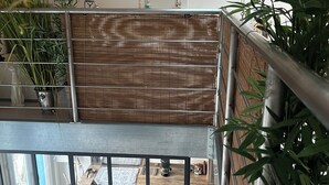 Un intérieur moderne agrémenté d’une cloison en bambou, d’un coin cuisine avec une machine à café et d’une vue sur l’espace repas grâce à une rambarde en verre.