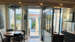 Une cuisine moderne dotée d’une grande fenêtre, un coin repas avec une table ronde et des chaises, et une vue sur le jardin extérieur.
