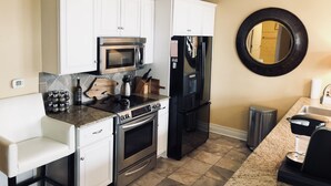 A kitchen with white cabinets, a stainless steel oven, a microwave, and a black refrigerator.