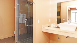 A modern bathroom with a glass-enclosed shower, a sink with a mirror, and a towel rack.
