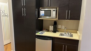 A compact kitchenette with a microwave, coffee maker, and dishwasher.