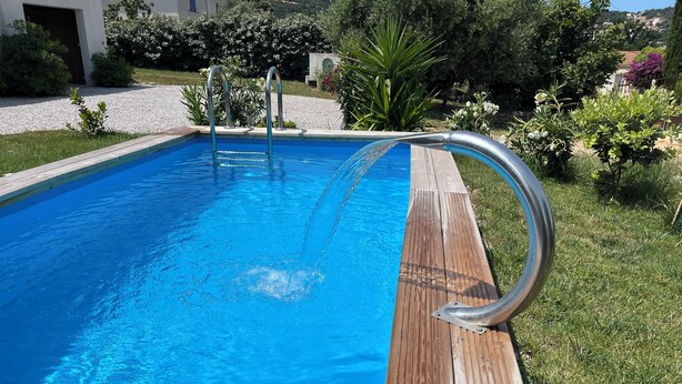 Ein rechteckiger Pool mit Holzterrasse und Metallhandläufen.
