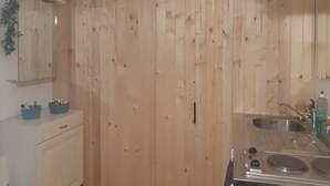 Eine Küche mit Holzwänden, einer Kleiderstange, einem Spülbecken und Schränken.