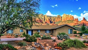 A two-story building with a stone facade, surrounded by a landscaped garden with various plants and rocks. - Uptown Sedona, Prime Location, HotTub VIEWS (Sedona)