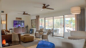 A spacious living room with a flat-screen TV, comfortable seating, and large windows offering a view of the outdoors. - Uptown Sedona, Prime Location, HotTub VIEWS (Sedona)