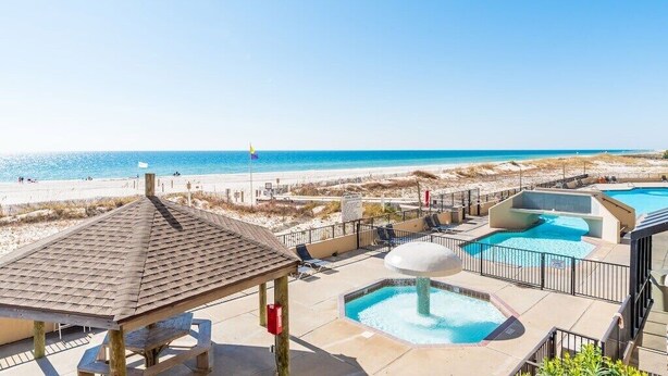 Un resort frente a la playa con zona de piscina, un pabellón y vistas a la playa y al océano.