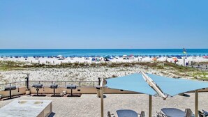 Un patio frente a la playa con mobiliario exterior y vistas al mar.