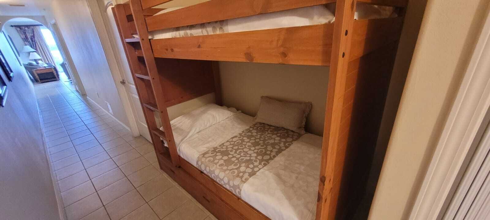 A bunk bed with a ladder, a patterned bedspread, and a pillow.